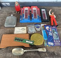 Mixed lot items spread on wooden surface showing watch bands, toys, collectibles, and electronic components