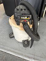 Preowned Rigid wet/dry shop vacuum, showing overall condition, white body, black top, hose, and wheels.