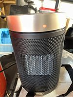 Front view of the black cylindrical ceramic heater with Dreo branding and metallic silver top.