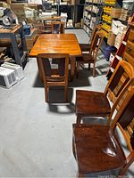 Dining table with six chairs arranged in a storage space, showing the overall set and condition.