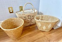 Three wicker rattan bags and one basket arranged on floor.