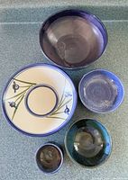 Top-down view of five assorted glazed pottery bowls showing colors and decorative details