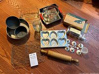 Photo of various bakeware including springform pans, glass bowls, glass measuring cup, piping set, cooling racks, rolling pin, and heart-shaped silicone molds