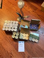 Full view of all candle packs and the floral votive candle holder on wood floor with handwritten lot tag
