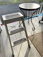 Metal step stool showing three textured steps and paint splatters