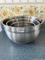 Four nested stainless steel mixing bowls showing PADERNO brand.