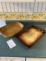 Two Pampered Chef stoneware items: a casserole dish and a flat rectangular dish with noticeable wear.