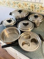 All items arranged to show the large pot, saucepans, steamer insert, and poached egg pan with lids.