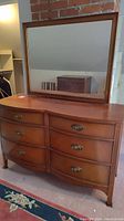 Full view of the dresser and matching mirror against wall showing dresser top and mirror reflecting room