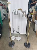 Four floor lamps: two vintage brass lamps with black marble bases, two silver IKEA metal lamps with round bases and dome shades.