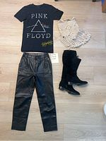 Full lot image showing Pink Floyd T-shirt, leather pants, fringe boots, crochet purse, and yellow heart-shaped glasses arranged on floor.