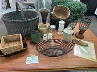 Photo showing assortment of baskets, jars, metal and ceramic kitchen items, candle votives, wooden shoe mold and fern print.