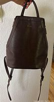 Front view of brown leather Mat & Nat backpack purse with visible texture and top handles.