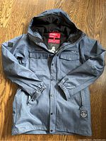Front view of dark gray-blue O’Neill jacket with hood, button and zipper closure, multiple pockets, elastic cuffs.