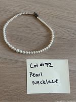 Full view of pearl necklace laid on a wooden surface showing pearl size gradient and overall necklace shape.