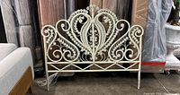 Front view of the spray painted vintage rattan peacock headboard showing the intricate scroll and coil work.