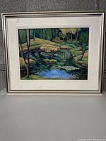 Full view of framed river bend painting showing scene of river, trees, and foliage with textured mat and light frame.