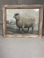 Full front view of framed artwork showing sheep, field, church steeple.