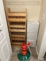 Red and green plastic wine drying rack standing upright next to wooden crates and cardboard boxes.