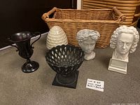 Full view of all six items including urns, busts, acorn statue, and wicker basket arranged on a surface.