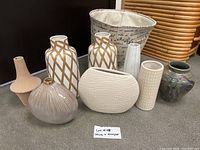 Full lot showing eight vases and fabric hamper with handwritten label 'Lot 418 Vases + Hamper' on grey carpet floor.