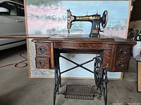 Full view of the antique White sewing machine with wooden cabinet and treadle base, showing extended work surface and drawers.