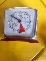 Front view showing white dial with markings for soccer, football, basketball, and red warning segment, under clear plastic cover