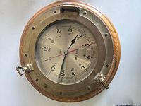 Full top view of the ship's porthole style clock showing brass frame and clock face.