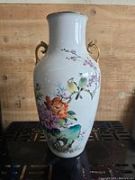 Front view of vintage Chinese porcelain vase showing hand painted colorful birds, flowers, and foliage with gold accent handles and rim.