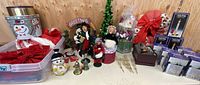 Wide shot showing multiple holiday decorations including Beyer Dolls caroling figures, tins, wreaths, hats, candle holders and boxes.