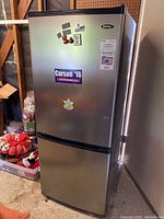 Front view of the Danby refrigerator showing upper fridge door and lower freezer door, magnets and stickers on front door.