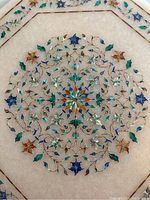 Close-up photo showing the detailed central floral mosaic inlay on white marble with multiple colors.