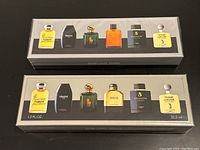 Two unopened rectangular fragrance gift sets side by side on a dark surface