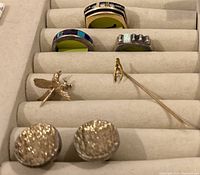 Jewelry tray holding all items: three rings, two pins and cufflinks