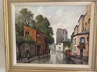 Framed oil painting of a rainy urban street landscape by artist Saulin with signature visible in lower right corner.