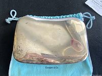 Top view of tarnished sterling silver lid resting on Tiffany dust bag