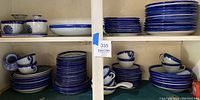 Multiple stacks of blue and white glazed stoneware plates and bowls with cups on shelf