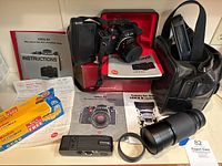 Overall lot on shelf: Leica R4 camera on box, attached lens, instruction manual, Leica boxes, leather bag, additional lenses, motor winder, film and receipts.