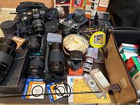 Overview of cameras, lenses, cases, filters, meter and accessories on table