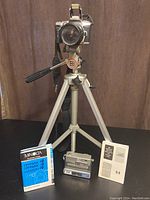 Minolta 35mm film camera, HP digital camera, camera tripod, and Minolta manual all displayed on a table