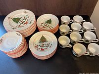 Overview of 10 complete place settings with plates, bowls, and cups in Christmas holiday pattern.