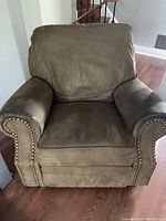 Front view of cafe mocha suede rocking recliner chair showing wear and nailhead trim on arms.