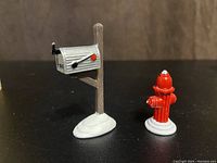 Photo of red mailbox on wooden post and red fire hydrant ceramic accessories with snow base
