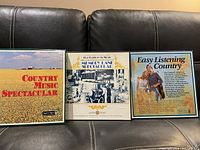 Three vinyl album boxed collections displayed on a black leather couch showing front cover artwork and titles.