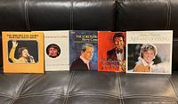 Five vintage vinyl albums arranged side by side on black couch, featuring cover images of Brenda Lee, Glen Campbell, Perry Como, Max Bygraves, and Anne Murray