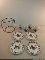 Set of 4 mugs and 4 plates with cardinal bird design and metal display rack on table