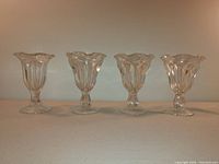 Set of four glass dessert/fountain glasses: three Anchor Hocking Fountainware glasses with ruffled tops and one additional parfait glass.