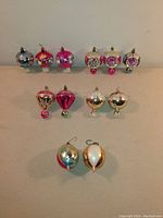 Front view of all 12 assorted glass ornaments laid out showing varying shapes, colors, and hand-painted details.
