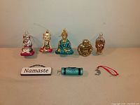 Front view of Buddha and yoga ornaments including cats, Buddha figures, 'Namaste' wooden sign, yoga mat, and Ohm symbol.