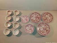 Top-down view showing all cups, saucers, and dinner plates arranged on table, clearly showing Red Willow pattern, sizes, and general condition.
